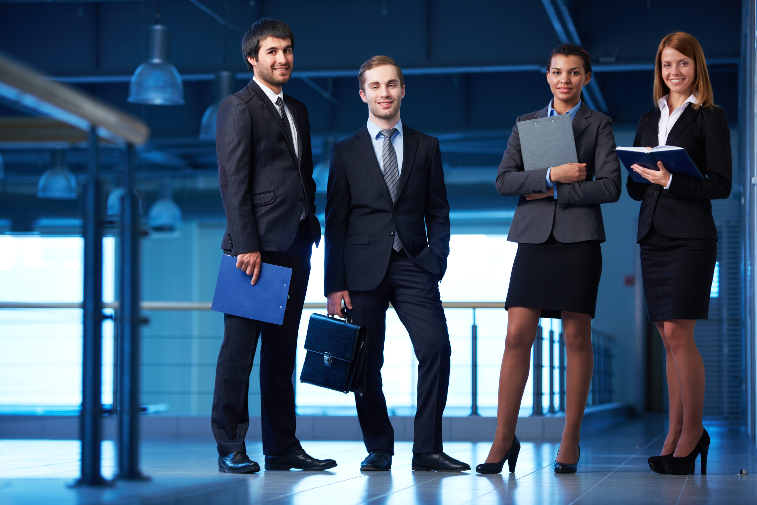 Group of friendly businesspeople in suits standing in line in office building